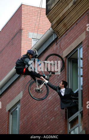 Mountain Bike Radfahrer Abseilen die Mauer eines Gebäudes mit Mann vom Bürofenster Edinburgh Schottland UK Stockfoto
