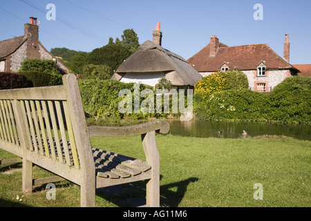 Holz- Sitzbank auf Country Village Green durch Teich in Singleton in der South Downs. West Sussex England Großbritannien Großbritannien. Stockfoto