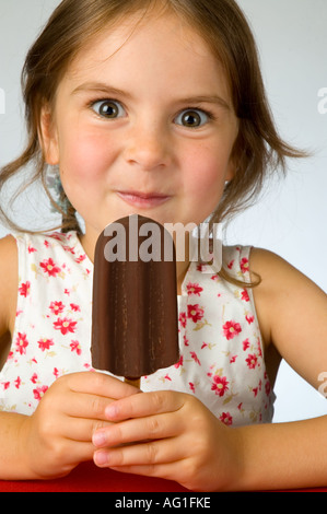 Kleine Mädchen genießen eine Schokolade bedeckte Eis Sahne-Eis am Stiel Stockfoto