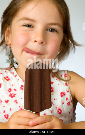 Kleine Mädchen genießen eine Schokolade bedeckte Eis Sahne-Eis am Stiel Stockfoto