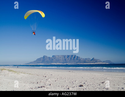 An einem hellen sonnigen windstillen s Wintertag nimmt eine motorisierte Hanglider in die Luft mit dem Tafelberg als Hintergrund Stockfoto