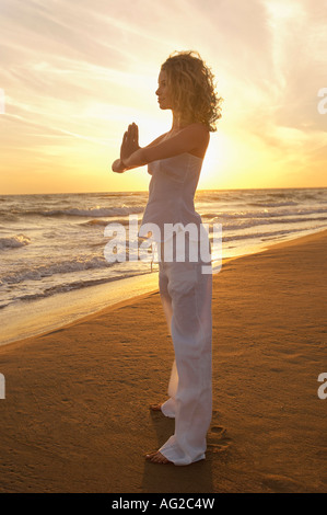 Junge Frau macht Tai Chi am Strand, Seitenansicht Stockfoto