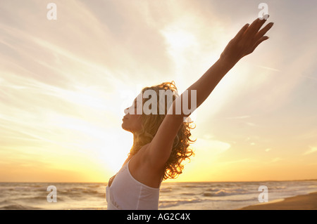 Junge Frau, die Strecken am Strand mit Augen geschlossen, seitliche Ansicht Stockfoto
