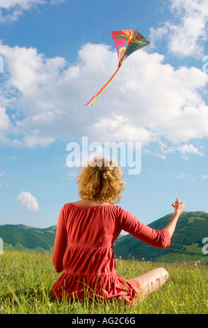 Frau im Berg Feld fliegende Drachen, Rückansicht Stockfoto