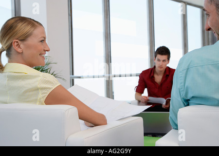 Frau lächelt Mann im Wartezimmer, Rückansicht Stockfoto