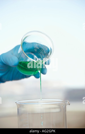 Wissenschaftler, die grünen Flüssigkeit in Becher, Nahaufnahme der Hand gießen Stockfoto