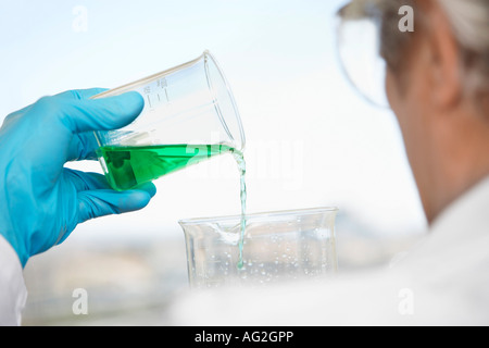 Wissenschaftler, die grünen Flüssigkeit im Labor, Fokus auf Seite gießen und Becher Stockfoto