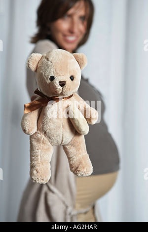 Schwangere Frau hochhalten Teddybär, drinnen Stockfoto