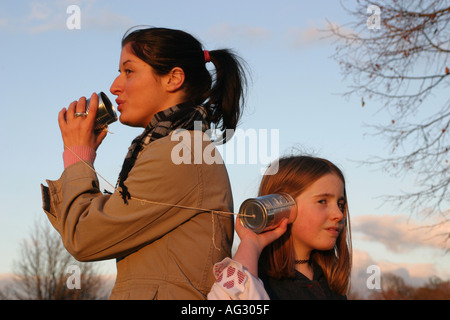 Junge Frau und Mädchen sprechen durch eine Blechdose Telefon Stockfoto