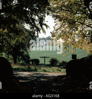 Ein Wiltshire Lane Wegweiser und Wald in herbstlichen Farben mit Ackerland jenseits Stockfoto