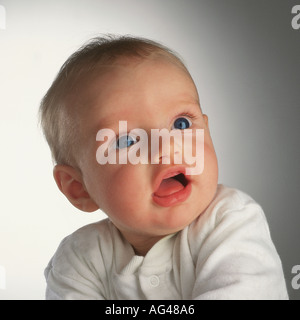 Sechs Monate alter Baby-Junge, der aufschaut. Keine Zähne. Große Augen. Studio-Aufnahme, einfacher Hintergrund. Stockfoto