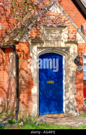 Hertfordshire, viel Hadham, alte Dorf Ferienhaus blaue Front Holztür, gebaut 1866 mit Frühling Blüte & Gartenblumen Stockfoto