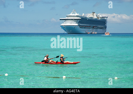 Kreuzfahrtschiff vor einer einsamen Insel in der Karibik, mit dem Kanu im Vordergrund verankert. Stockfoto