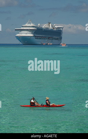 Kreuzfahrtschiff vor einer einsamen Insel in der Karibik, mit dem Kanu im Vordergrund verankert. Stockfoto