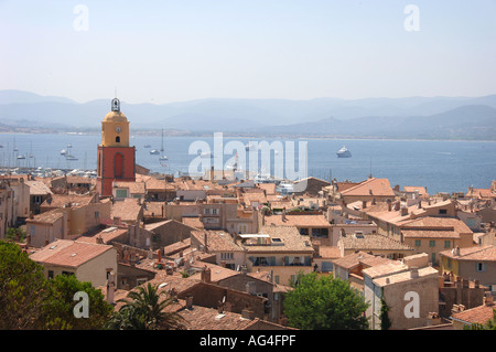 Blick auf die Stadt von Saint Tropez an erhöhter Lage in der Nähe der Zitadelle hinter der Kirche, mit dem Meer im Hintergrund mit Yachten und Boote. Stockfoto