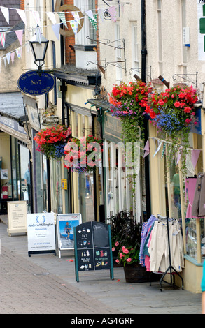 Geschäfte mit hängenden Blumenkörben außerhalb auf der Haupteinkaufsstraße von Chepstow Monmouthshire South East Wales UK Stockfoto