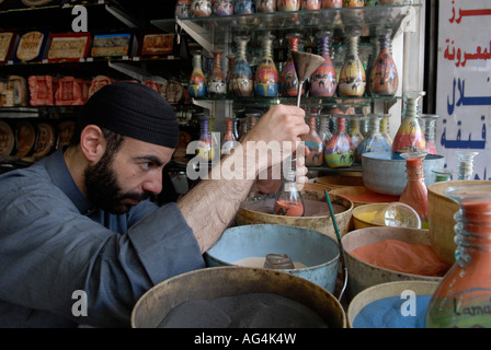 Jordanische Mann fügt farbige Sand eine dekorierte Flasche mit bunten Sand Felsen gefüllt, die in Petra in einem Souvenirshop in Amman Jordanien gefunden wird Stockfoto