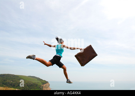 Junges Mädchen scheinbar Sprung von einer Klippe Sarah Klein mit Koffer Stockfoto