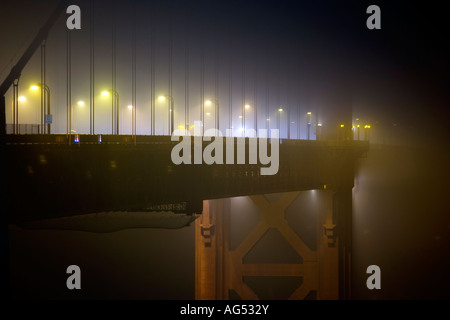 Die Golden Gate Bridge mitten im Nebel in der Nacht erstrahlt von Straßenlaternen und Verkehr Stockfoto