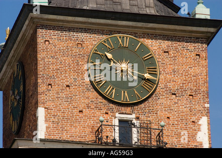 Turm des Rathauses mit alter Uhr auf dem Hauptmarkt in Krakau Polen. Historische Backsteinarchitektur und verzierte goldene Uhr. Stockfoto