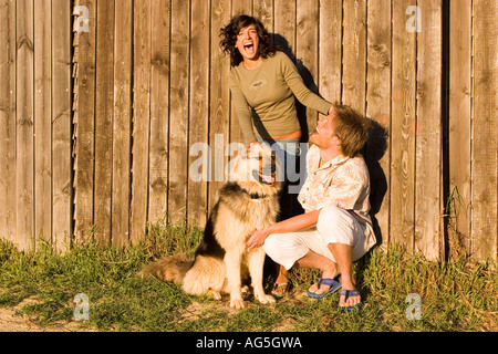 Ein paar genießen Sie ihren Hund mit Holzzaun Hintergrund Stockfoto