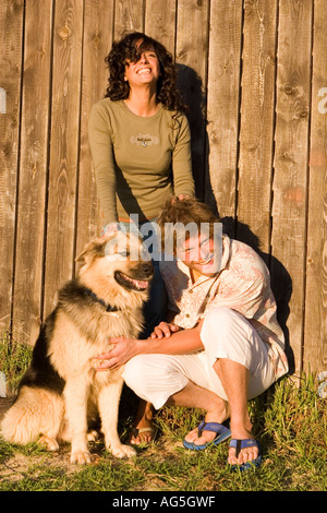 Ein paar genießen Sie ihren Hund mit Holzzaun Hintergrund Stockfoto