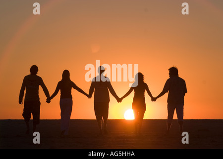 Gruppe der besten Freunde Hand in Hand gehen in den Sonnenuntergang Stockfoto