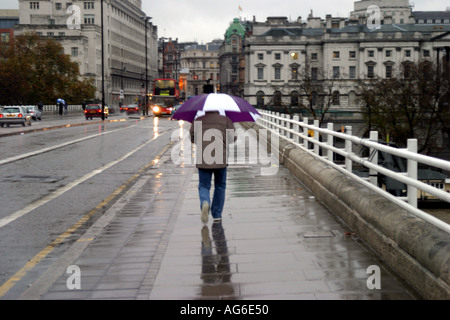 Einzelne Person zu Fuß über die Waterloo Bridge in London im Regen Stockfoto