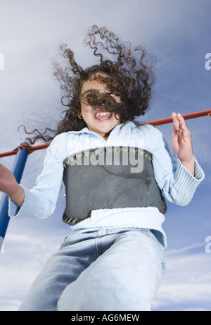 Mädchen schwingen mit Haare fliegen hoch zufrieden Gesicht lächelnd blauer Himmel Hintergrund offbeat Stockfoto