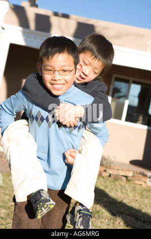 japanische großer Bruder geben Geschwister Huckepack Fahrt im Freien, glücklich lächelnd Stockfoto