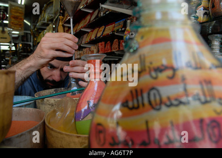 Jordanische Mann fügt farbige Sand eine dekorierte Flasche mit bunten Sand Felsen gefüllt, die in Petra in einem Souvenirshop in Amman Jordanien gefunden wird Stockfoto