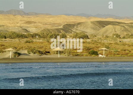 Ägypten Rotes Meer zwischen Quoseir und Marsa Alam Sonnenschirme am Sandstrand bei Sonnenaufgang Stockfoto