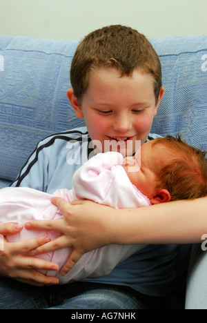 8 Jahre alter Junge wiegt seine Neugeborenen 4 Tage alte Schwester, Middlesex, UK. Stockfoto