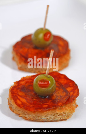 Tapa dünne Scheiben der Chorizo Iberico de Bellota mit Piment-gefüllte Oliven in Olivenöl knusprig gebratenes Brot. Stockfoto