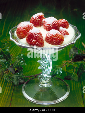 Erdbeeren und Sahne, ein typisches Dessert der Sommerzeit auf einem grünen Hintergrund Holz Stockfoto