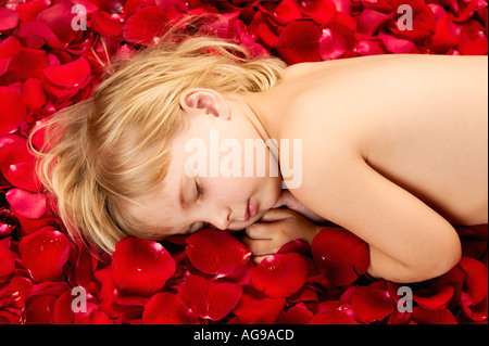 Kind 4 Jahre alt auf Rosenblättern liegen Stockfoto