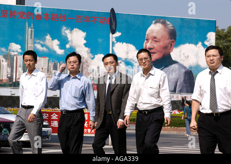 Büroangestellte gehen vor ein Wandbild von Deng Xiao Ping, das erinnert an die Gründung von Chinas erste Special Economic Zone 2 Stockfoto