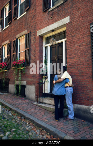 Paar umarmt vor Brownstone Wohnungen auf historischen Fluss Stein gepflastert Eichel Straße am Beacon Hill Boston MA Stockfoto