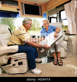 Älteres paar sitzen in RV Karte schauen und Lächeln Stockfoto
