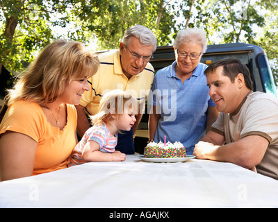 Drei Generationen kaukasische Familie am Picknicktisch weibliche Kinder Geburtstag Kuchen sitzen Stockfoto