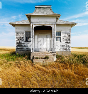 Fassade des verwitterten verlassenen Gebäude mit abblätternde Farbe im Grasland Stockfoto