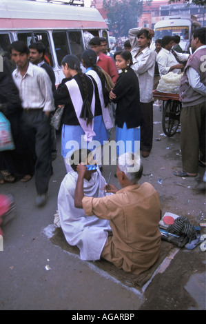 Indien, Rajasthan, Jaipur, Barber auf Straße mit Menschen und Bussen im Hintergrund Stockfoto