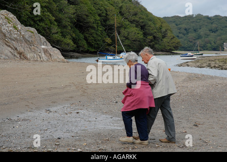 Älteres Ehepaar zu Fuß am Strand Arm in arm Stockfoto