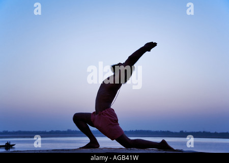 Berühmte Yogi Weltlehrer Dr. Rakesh Yogi in Virbhadrasana Yogastellung Ganges Fluß Indien Stockfoto