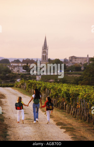 Mutter und Töchter, vorbei an Weinbergen von Bordeaux am Weg zur Schule im Dorf von St. Emilion, Frankreich Stockfoto