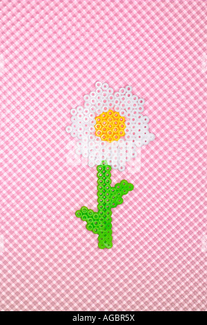 Weiße Kunststoff Blume aus Perler Perlen auf einem rosa Hintergrund hergestellt. Stockfoto