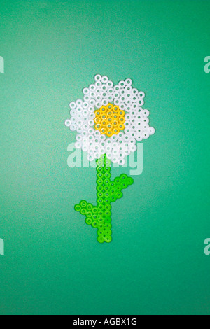 Kunststoff Blume aus Perler Perlen auf einem grünen Hintergrund hergestellt. Stockfoto