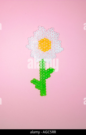 Kunststoff Blume aus Perler Perlen auf einem grünen Hintergrund hergestellt. Stockfoto