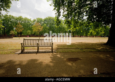 Einsame Holzbank in der Nähe von einem großen Baum im Hyde Park, London Stockfoto