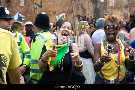 Zwei freche, modische junge schwarze Mädchen, die Spaß an der Notting Hill Carnival 2007 während Polizisten schauen auf. Stockfoto